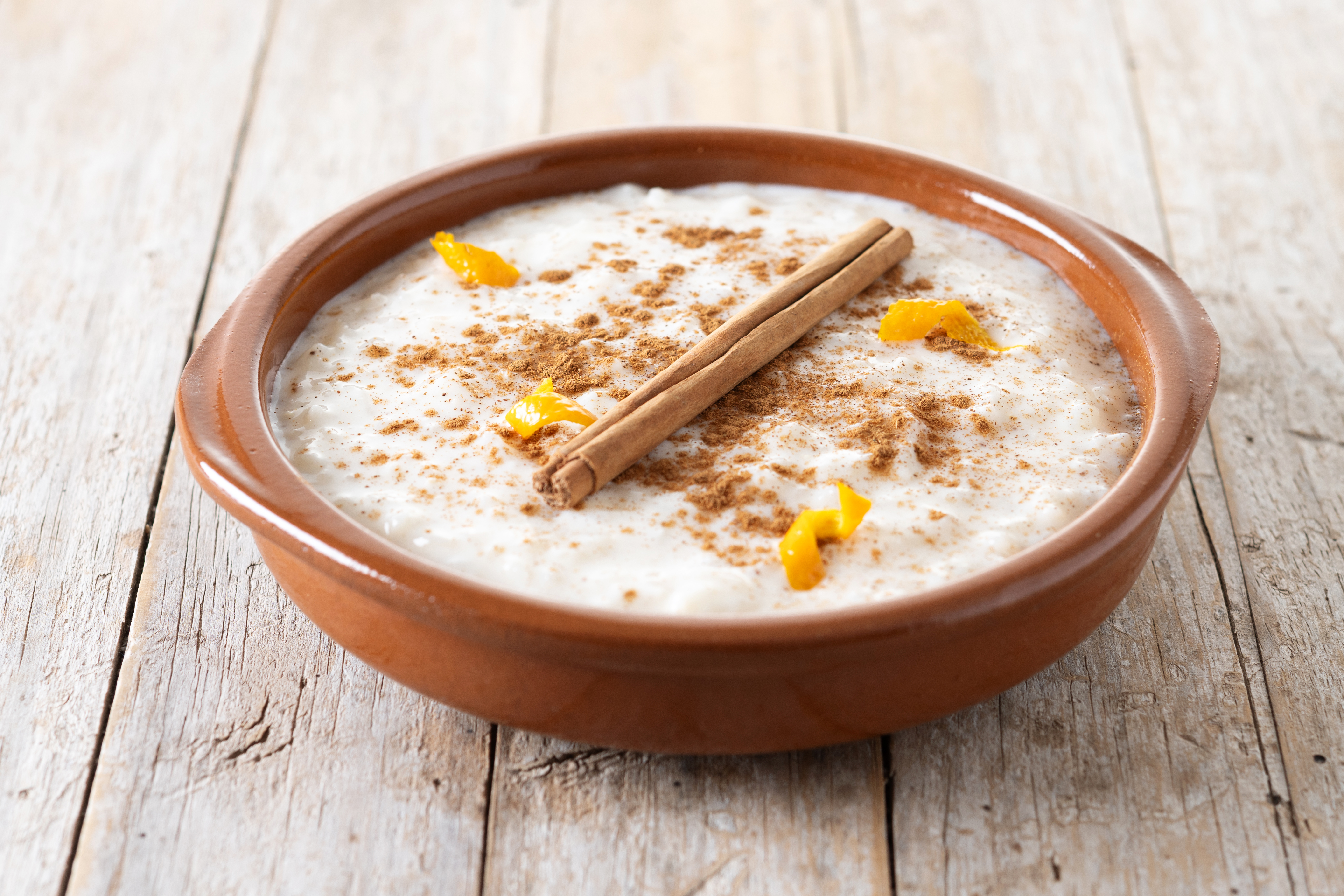 Arroz con leche fitness en un cuenco de barro, canela, limón y palo de canela